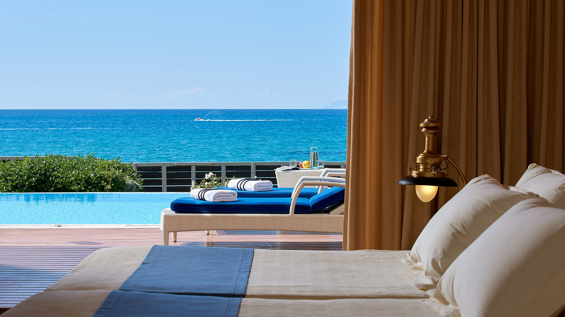 View from the bed to a terrace with sunbed, pool and the blue Ionian Sea